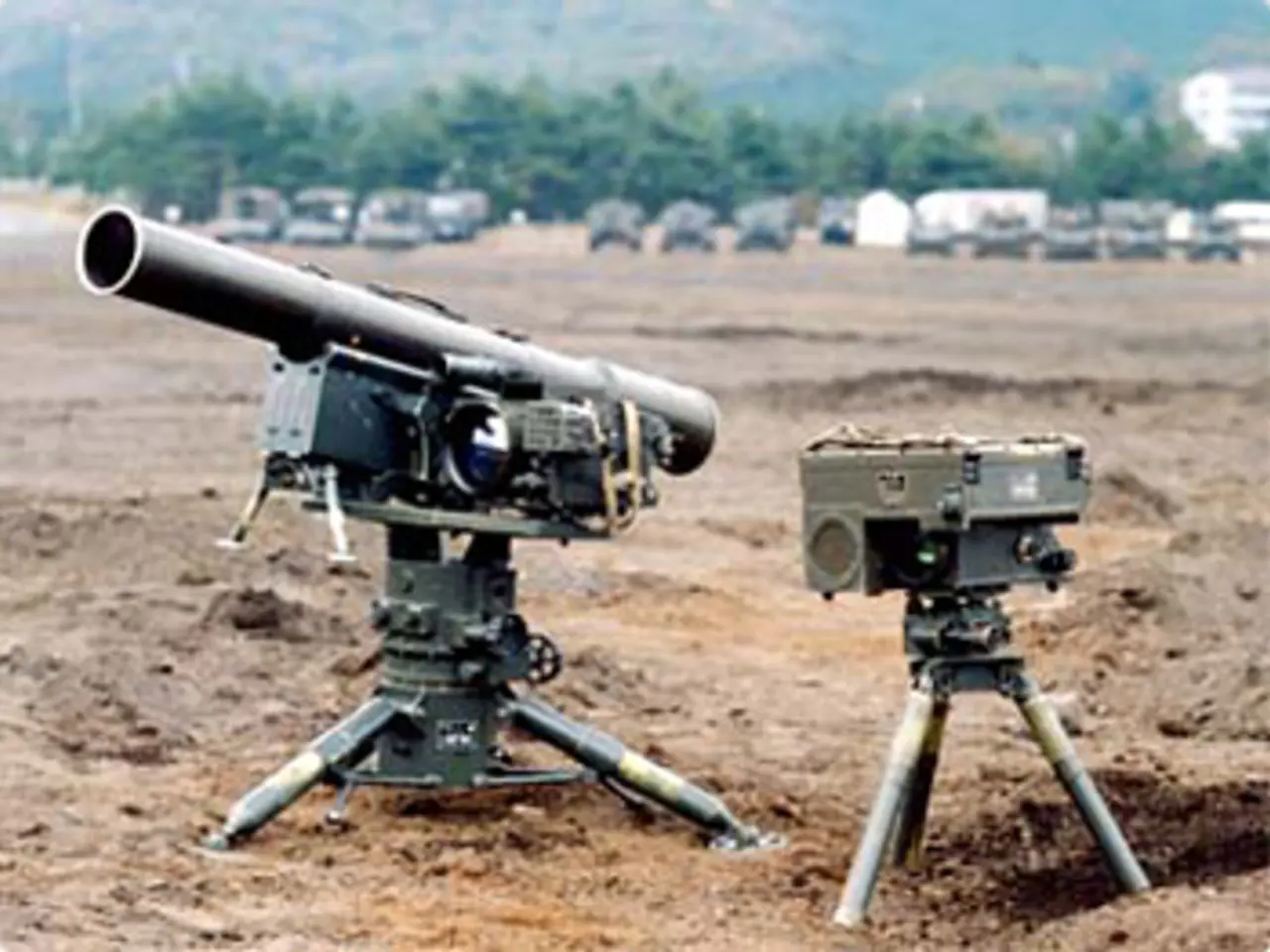 There is a missile system arranged on the ground. In the background, there are vehicles parked,...