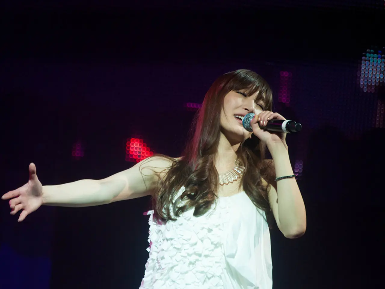 There is a woman. She is standing. She is wearing a white top, her hair color is brown. She is...