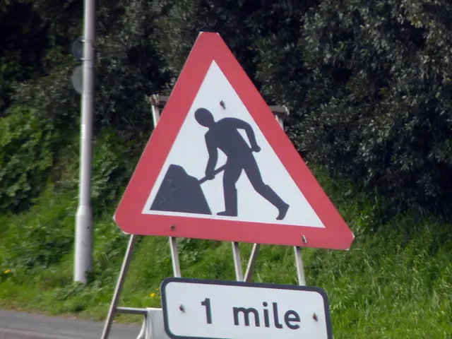 In this image we can see a sign board attached to the stand on the pavement and there are few bags...