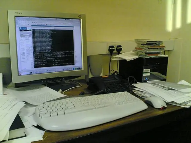 In this picture we can see table and on table we have papers, book, keyboard, mouse, telephone,...