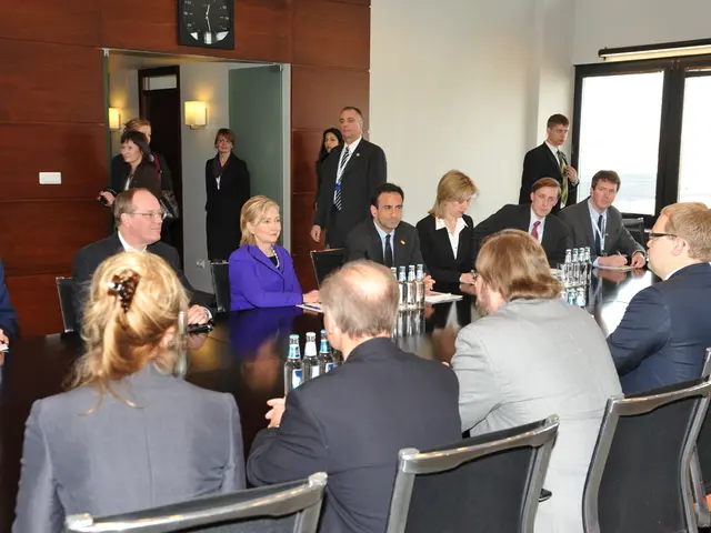 In this picture there is a group of men and women sitting in the conference hall. In the center we...
